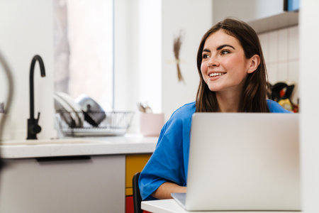 Lovely smiling young woman working on laptop computer from homeの写真素材