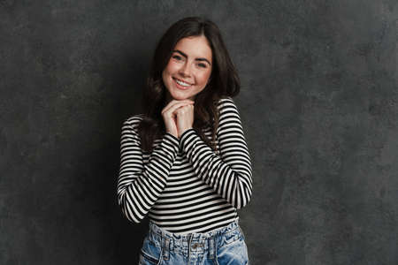 Portrait of happy smiling lovely woman dressed in casual wear standing over isolated background,...