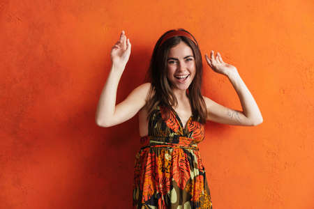 Beautiful young woman in summer dress posing over isolated background, dancingの写真素材