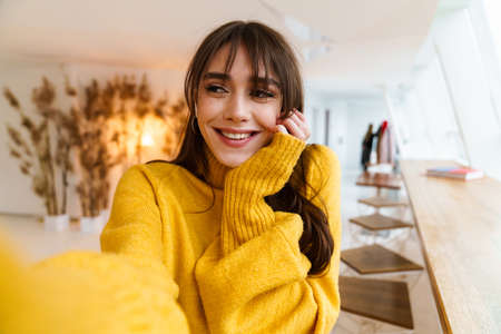 Charming happy nice girl taking selfie photo and smiling indoors