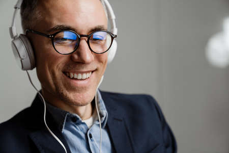 Cheerful grey man in headphones smiling while having break at office