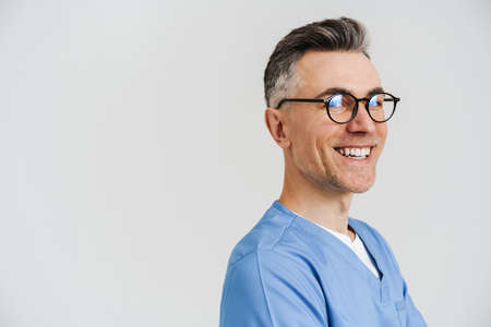Happy white-haired medical doctor smiling at camera crossed isolated over white wall