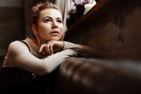 Young caucasian beautiful woman looking aside while sitting indoors