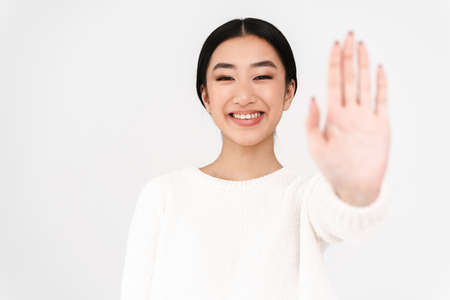 Asian cheerful nice girl smiling and showing stop gesture isolated over white backgroundの写真素材