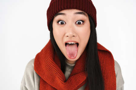 Asian excited nice girl showing her tongue at camera isolated over white backgroundの写真素材