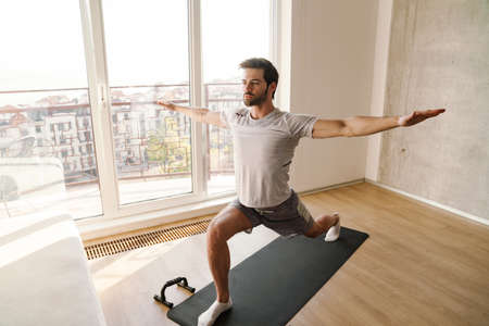 Focused athletic man doing exercise while working out with push-up stops at home