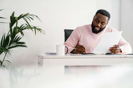 Afro american businessman talking on mobile phone while sitting at the office desk
