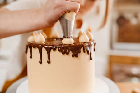 Caucasian pastry chef woman making cake with chocolate cream indoorsの写真素材