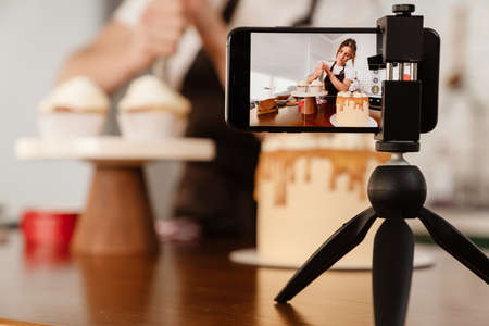 Camera footage of focused baker woman making cakes with cream in kitchenの写真素材