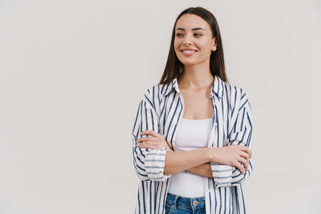 Happy beautiful brunette girl smiling while posing with arms crossed isolated over white background