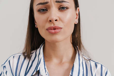 Unhappy beautiful brunette girl posing and looking at camera isolated over white backgroundの写真素材