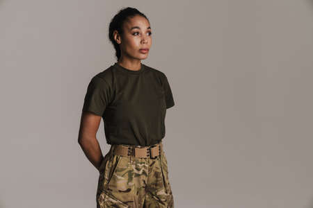 Confident african american soldier woman posing and looking aside isolated over grey wall
