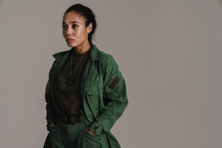 Confident african american soldier woman posing with hands in her pockets isolated over grey wallの写真素材