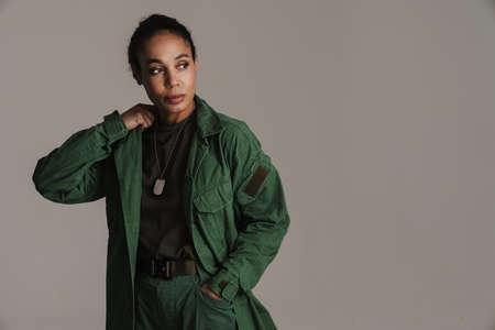 Confident african american soldier woman posing and looking aside isolated over grey wallの写真素材