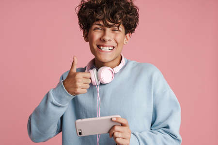 Close up of an attractive young teenager listening to music with his headphones isolated against...