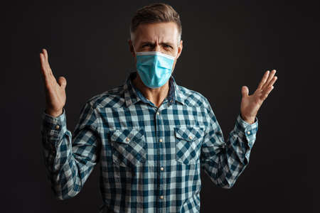 Photo of screaming angry grey-haired man wearing face mask isolated over grey wall background