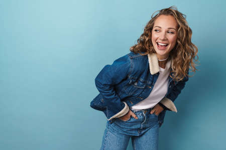Blonde happy woman laughing and looking at camera isolated over blue wallの写真素材