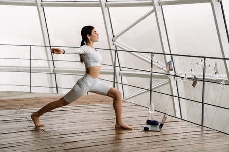 Young white woman using laptop during yoga practice indoors