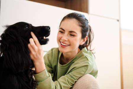 Happy young brunette woman with her dog at homeの写真素材
