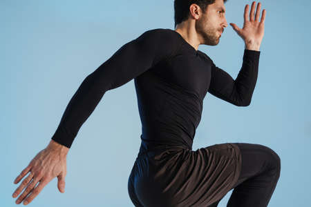 Young athletic sportsman doing exercise while working out isolated over blue background