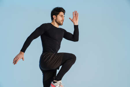 Young athletic sportsman doing exercise while working out isolated over blue backgroundの写真素材