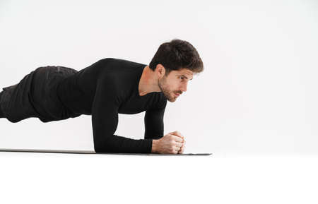 Young athletic sportsman doing exercise while working out on mat isolated over white background