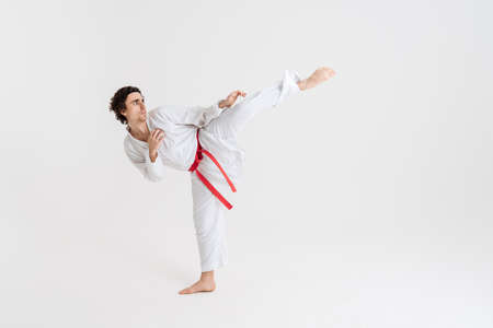 Young caucasian sportsman dressed in kimono practice in karate isolated over white backgroundの写真素材