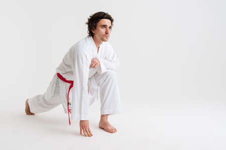 Confident young karate man warming up isolated over white backgroundの写真素材