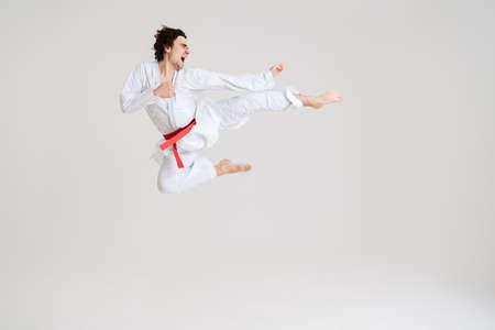 Young caucasian sportsman dressed in kimono practice in karate isolated over white backgroundの写真素材