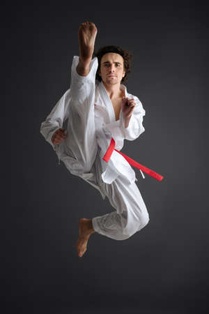 Young caucasian sportsman dressed in kimono practice in karate isolated over gray backgroundの写真素材
