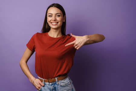 Cheerful young attractive woman pointing fingers at herself isolated over violet backgroundの写真素材