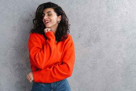 Happy beautiful brunette girl posing and smiling at camera isolated over grey wallの写真素材