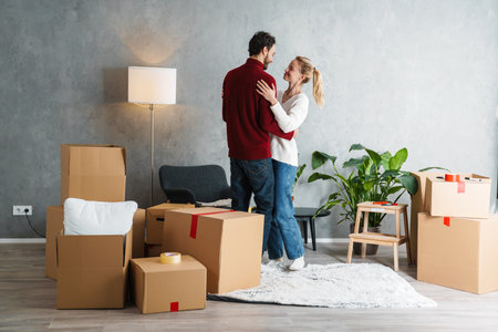 Portrait of a smiling couple moving together in a new house surrounded with boxes, dancingの写真素材