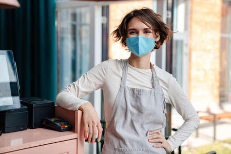 Happy female cafe owner wearing protective face mask, reopening after coronavirus epidemicの写真素材