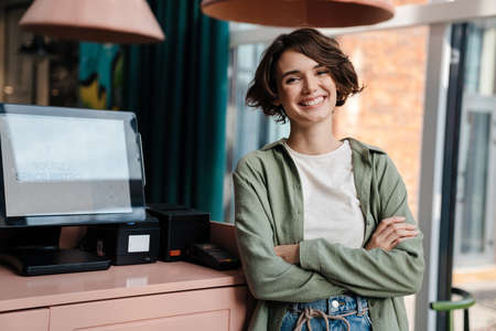Cheerful beautiful girl laughing and looking at camera in cafe indoorsの写真素材
