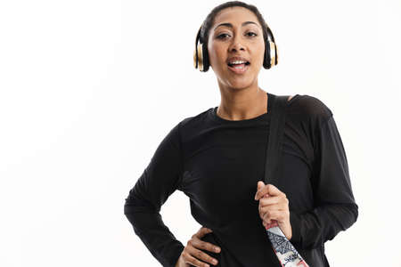 Pleased african american woman singing while listening music with headphones isolated over white backgroundの写真素材