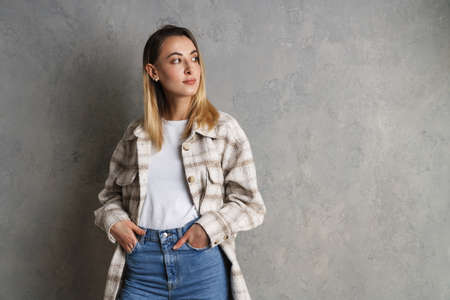 Happy casual girl looking away at copy space isolated over gray backgroundの写真素材