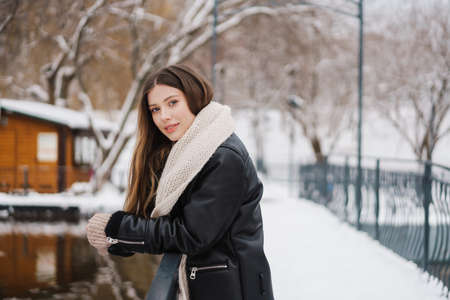 Happy beautiful girl smiling and looking at camera while walking in winter parkの写真素材