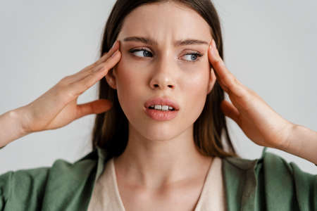 Displeased caucasian girl with headache rubbing her temples isolated over white backgroundの写真素材