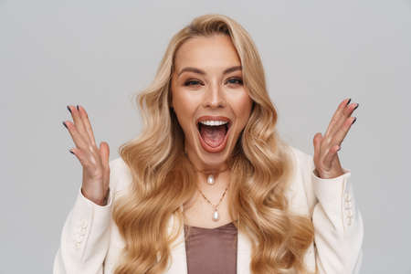 Beautiful excited girl in jacket screaming at camera isolated over grey backgroundの写真素材