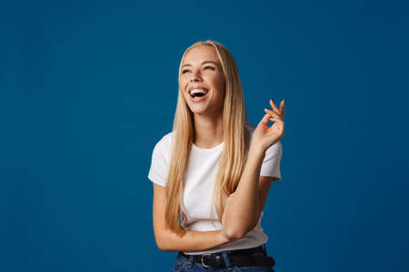 Blonde young happy woman laughing while posing on camera isolated over blue backgroundの写真素材