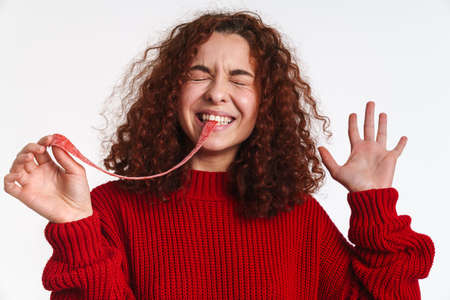 Excited ginger young woman making fun with gummy isolated over white backgroundの写真素材