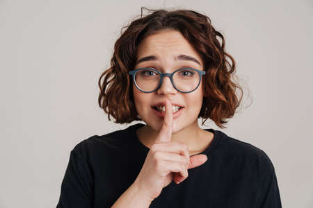 Lovely young girl showing silence gesture isolated over gray background