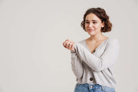 Portrait of a lovely young attractive smiling woman in casual wear posing isolated over white background, looking away at copy spaceの写真素材