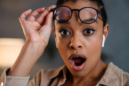 Close up of a happy young schocked african business woman looking at camera indoorsの写真素材