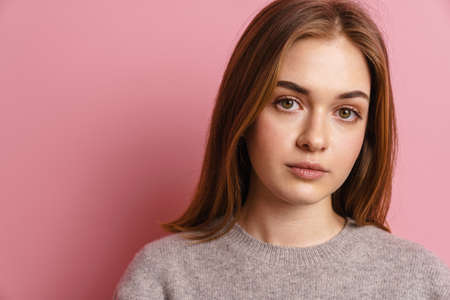 Young ginger european woman posing and looking at camera isolated over pink backgroundの写真素材