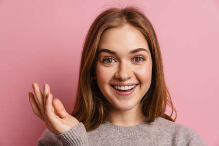 Young ginger happy woman smiling and looking at camera isolated over pink background