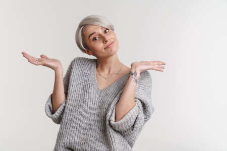 Confused beautiful silver girl showing and holding copyspace isolated over white backgroundの写真素材