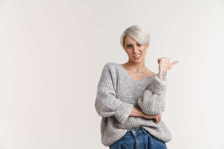Confused beautiful silver girl grimacing and pointing finger aside isolated over white backgroundの写真素材