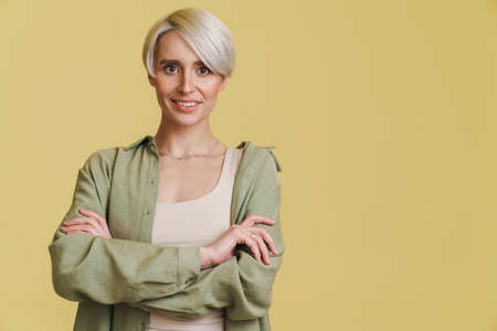Young white-haired woman smiling and looking at camera isolated over beige backgroundの写真素材